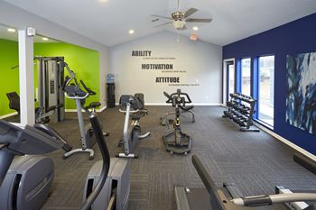 A gym with a green wall and a sign that says "Ability Motivation Attitude".